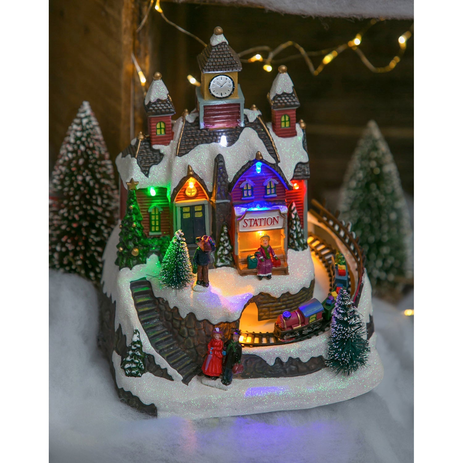 Christmas village train station lit up with colorful LED lights in a snowy holiday setting