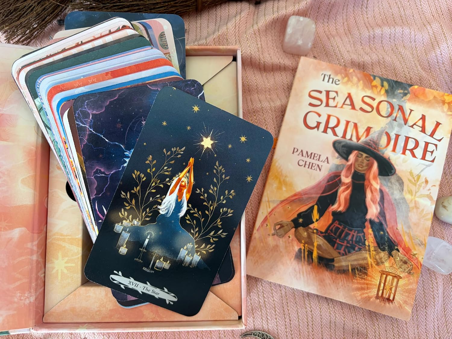 Witches of the Seasons Tarot cards fanned in the open box with The Star in front, next to the Seasonal Grimoire