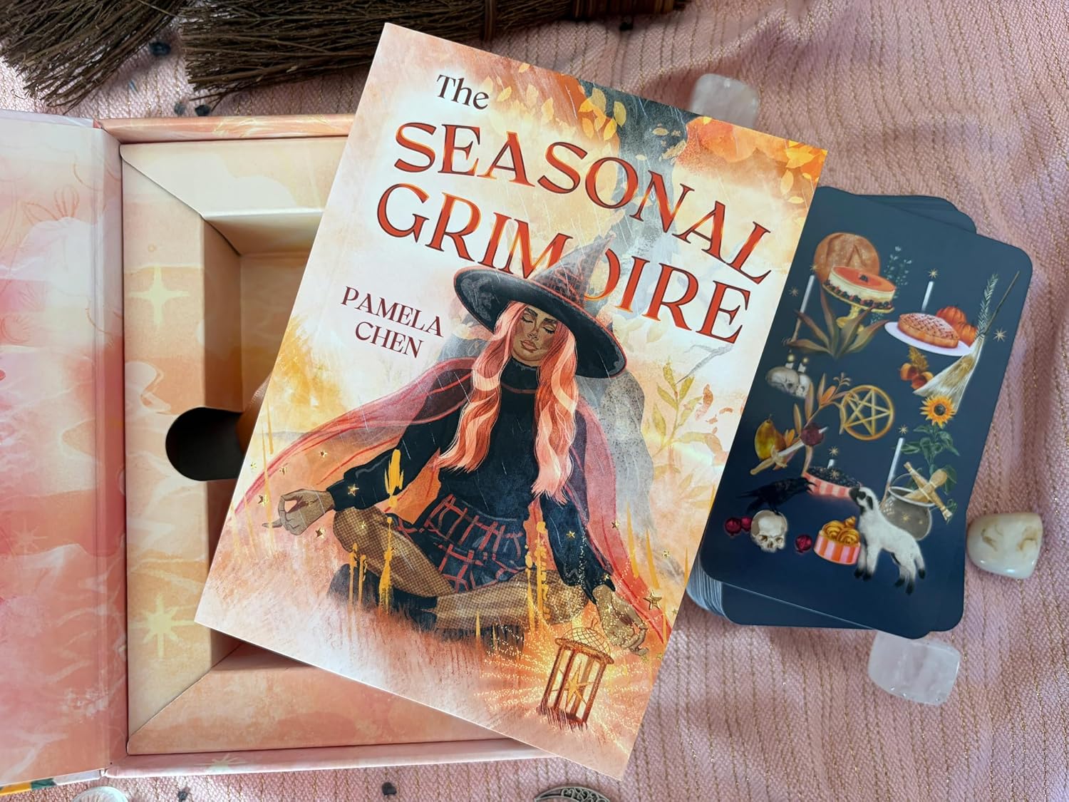 Open Witches of the Seasons Tarot box with The Seasonal Grimoire guidebook resting on top beside the deck