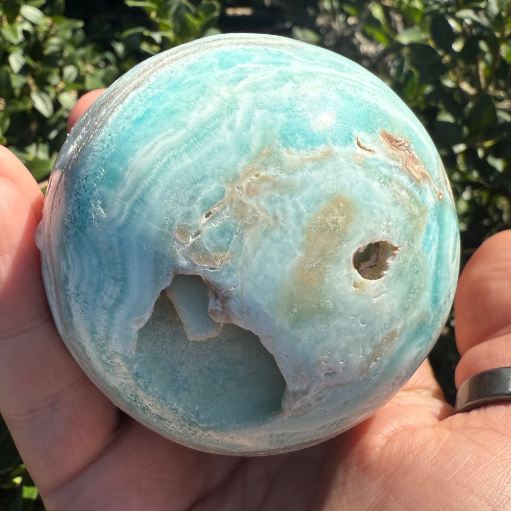 Hand holding a blue and white marbled stone with a natural background