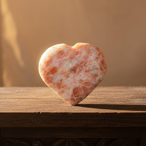 Heart-shaped orange and white stone held in a hand against a white background