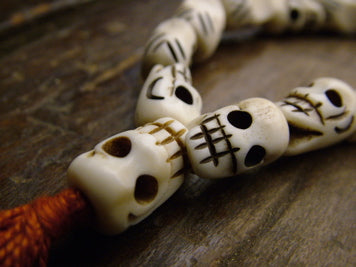 These very long mala beads are quite striking. They are made of water buffalo bone hand-carved to look like skulls and features a red rayon tassel.