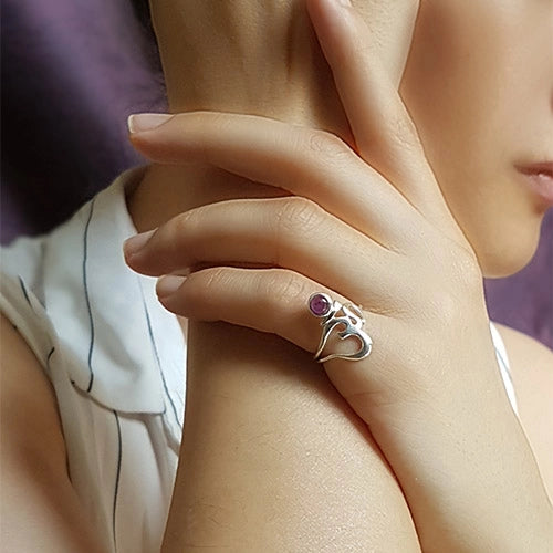 Om Symbol Ring with amethyst worn on a woman's finger, hand resting on her arm