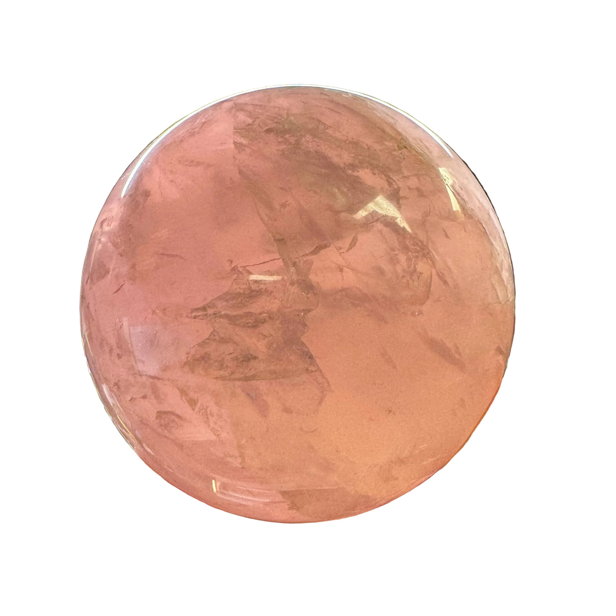 A hand holding a large, polished pink quartz crystal sphere with visible internal inclusions, photographed in a cluttered workshop or storage environment with a bright light fixture above.