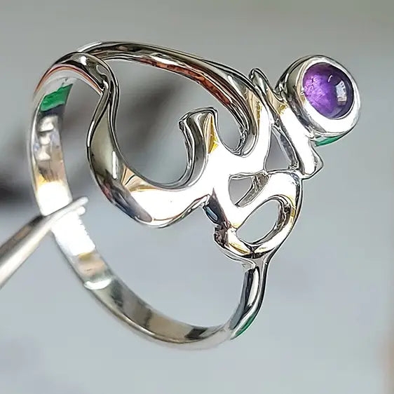 Om Symbol Ring close-up showing the polished silver Om design and a round purple amethyst