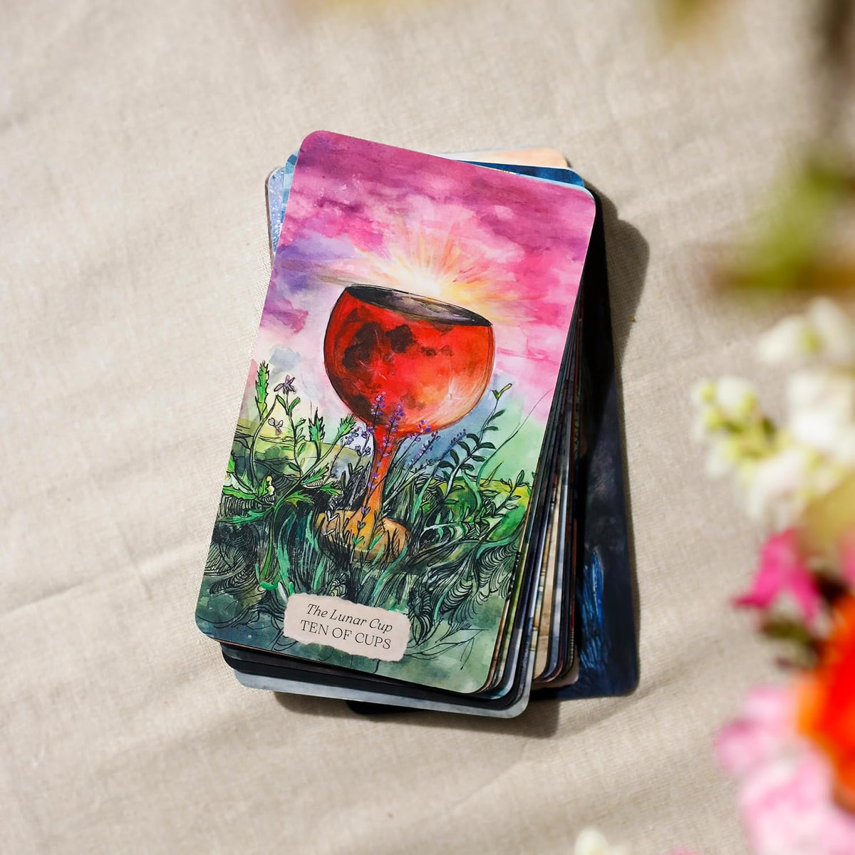 Ten of Cups card, The Lunar Cup, on top of a stack of Bonestone & Earthflesh Tarot cards