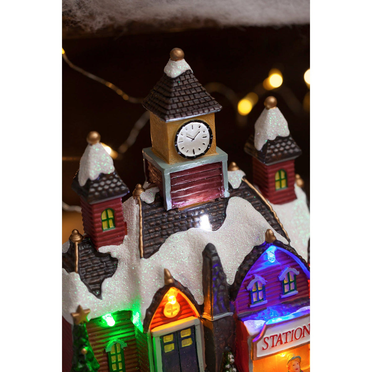 Close-up of the clock tower and snowy rooftops on the Christmas village train station