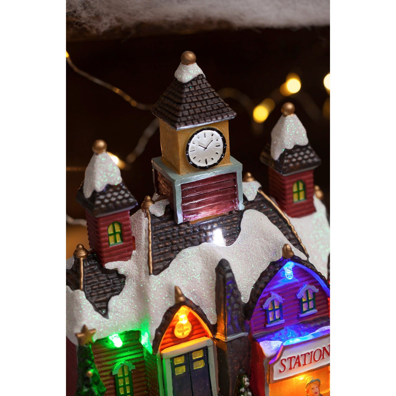Close-up of the clock tower and snowy rooftops on the Christmas village train station
