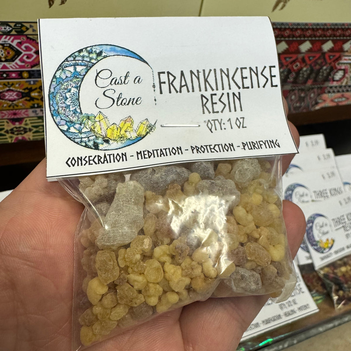 Bag of frankincense resin held by a hand with 'Cast a Stone' label.