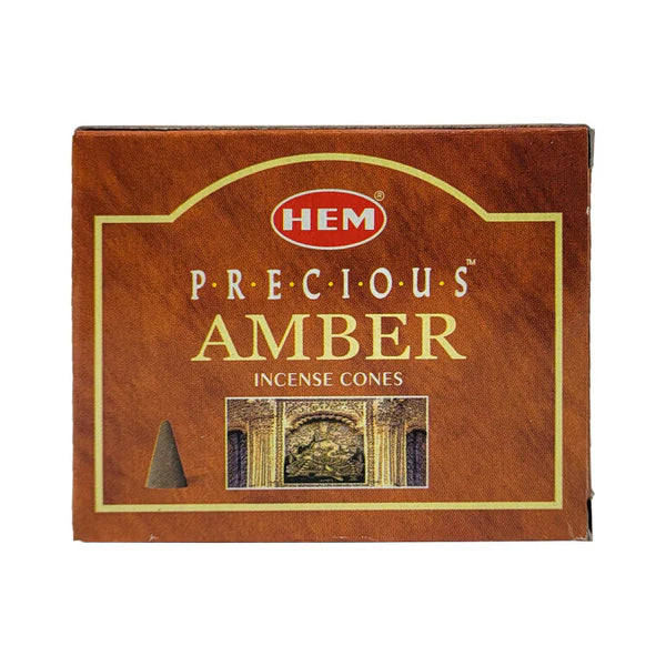 Box of HEM Precious Amber incense cones on a wooden surface with an incense cone in front.
