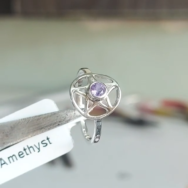 Amethyst Pentacle Ring held in tweezers: a faceted purple stone in an open silver pentacle setting