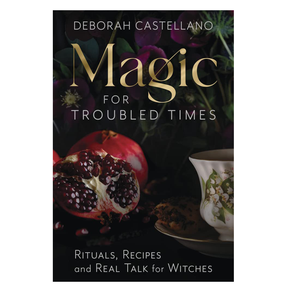 Book cover of 'Magic for Troubled Times' by Deborah Castellano with a pomegranate and teacup on a dark background.