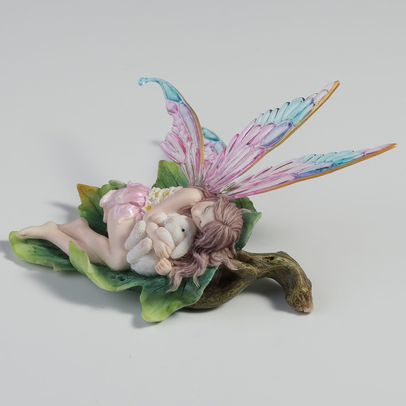 Fairy figurine with colorful wings and a teddy bear on a white background