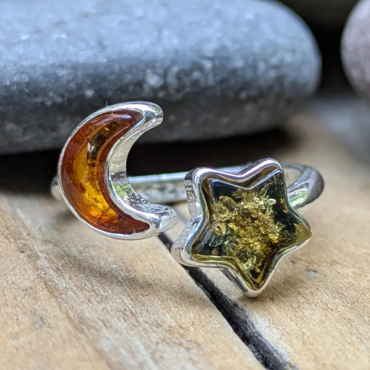 Silver ring with amber inlay featuring a moon and star design on a stone surface.