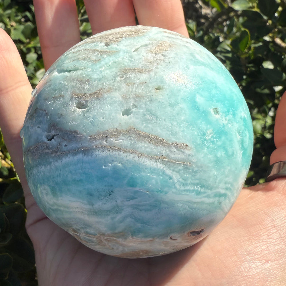 Hand holding a blue-green stone against a natural background