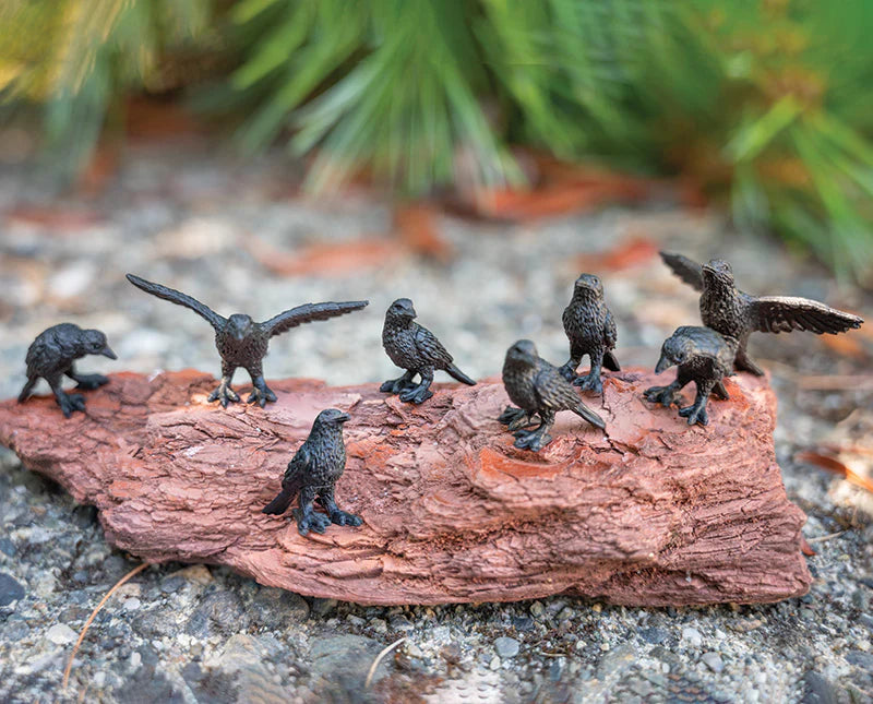 Small bird figurines on a piece of wood with a natural background