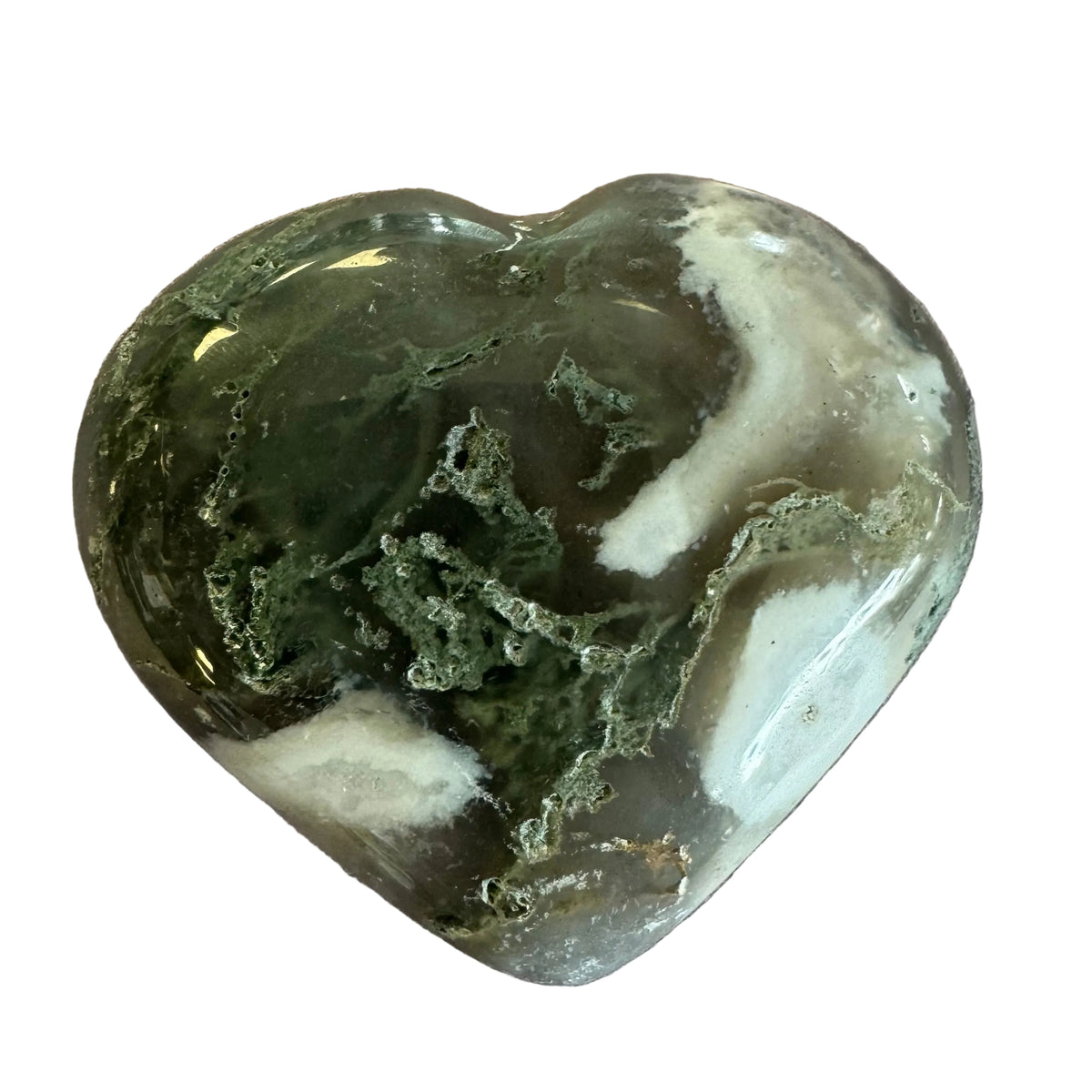 A polished heart-shaped crystal stone with natural marbled patterns of dark green, translucent gray, and white, resting on a textured light brown surface.