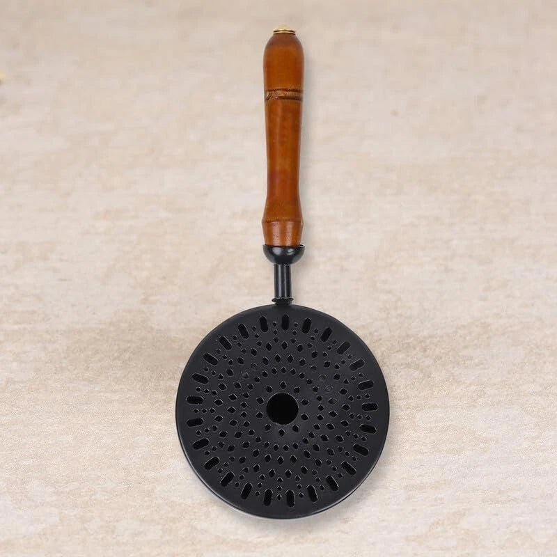 Black incense burner with a wooden handle on a beige background