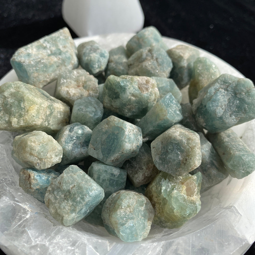 Collection of blue green crystals on a white plate with a dark background