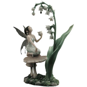 The Lily of the Valley Statue By Rachel Anderson captures a charming scene in which a fairy waits patiently for a drop of dew to fall from one bell-shaped flower. Sitting atop a brown toadstool, the fairy wears a light green tunic with a chain of pearls and a teardrop pendant hanging from her neck. 