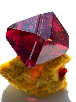 This stunning red crystal is Polish Pruskite. It is lab-grown out of natural elements. It is a single large red crystal on top of a yellow base. It is a beautiful bright color and will bring bright energy to any room it is in.