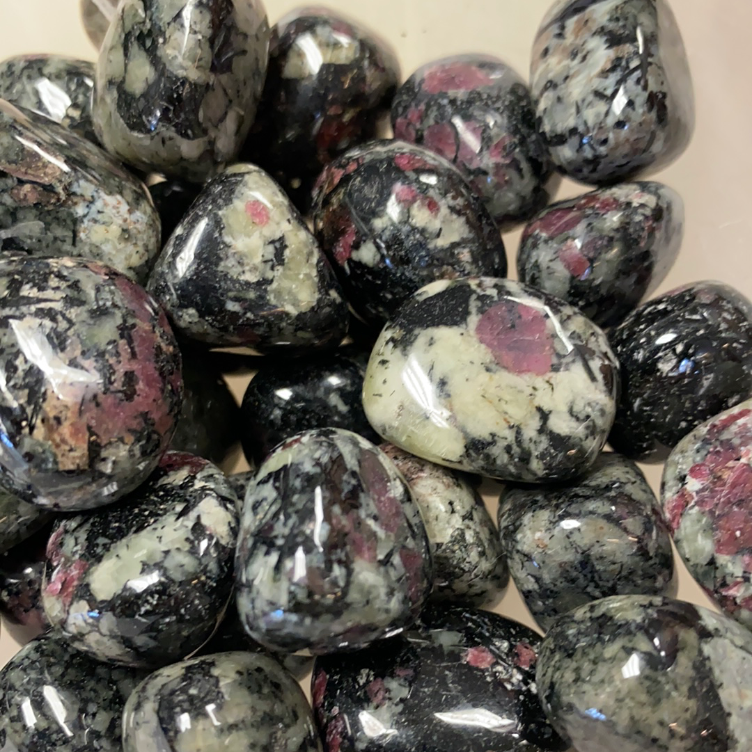 A tumbled Eudialyte gemstone, believed to stimulate the heart chakra and promote feelings of love