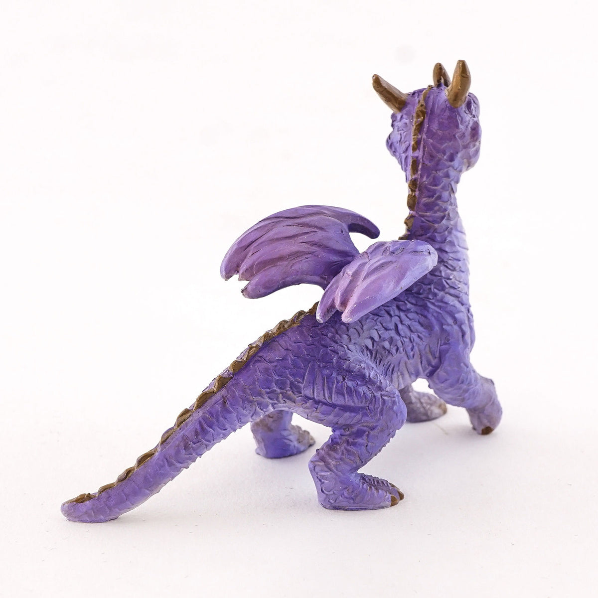 It is standing on all fours and has a simultaneously adorable and majestic appearance. He has purple scales and a white underbelly, along with yellow eyes, three horns on its head, and a ridge of spikes down the winged back. It’s a lovely dragon that will be at home anywhere.