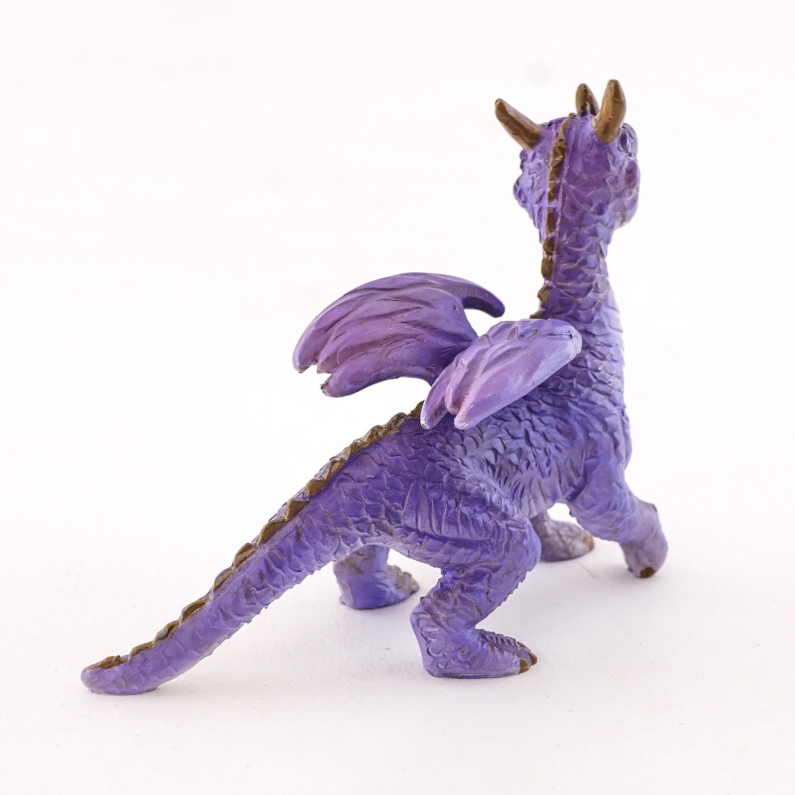 It is standing on all fours and has a simultaneously adorable and majestic appearance. He has purple scales and a white underbelly, along with yellow eyes, three horns on its head, and a ridge of spikes down the winged back. It’s a lovely dragon that will be at home anywhere.