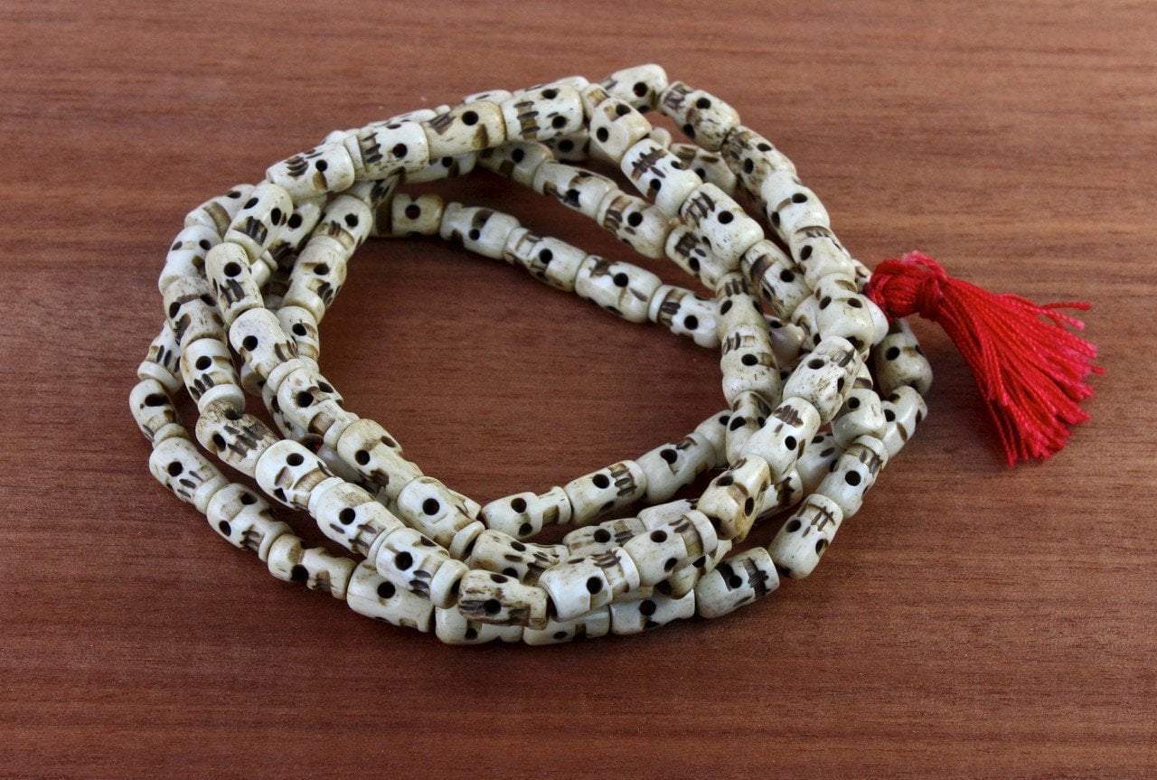 These very long mala beads are quite striking. They are made of water buffalo bone hand-carved to look like skulls and features a red rayon tassel.