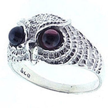 A sterling silver owl ring with a garnet eye, surrounded by intricate owl features and a band.